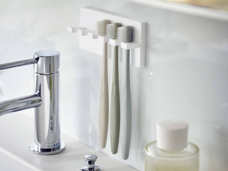 MISTの5連フィルムフック歯ブラシホルダーが光沢のある壁面に取り付けられ、歯ブラシを整理している様子