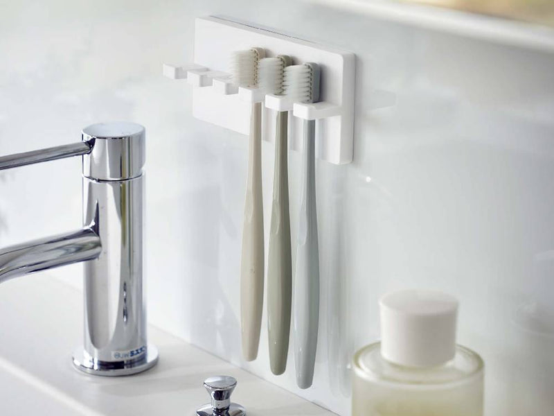 MISTの5連フィルムフック歯ブラシホルダーが光沢のある壁面に取り付けられ、歯ブラシを整理している様子
