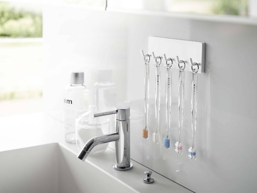 MISTフィルムフック5連セットが、銀色のステンレスガラス面に取り付けられている様子。耐荷重500gで浴室やキッチンの整理に最適です。