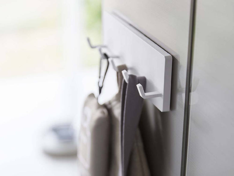 シルバー色のミスト5連フィルムフックが光沢のある平らな壁面に取り付けられている様子