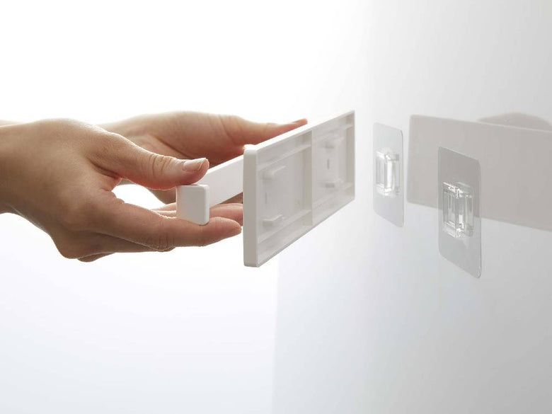 MISTのフィルムフック タオルハンガー W18が、光沢のあるプラスチック壁面にしっかりと取り付けられている様子。ABS樹脂製の本体と透明なフィルムフックが特徴的。