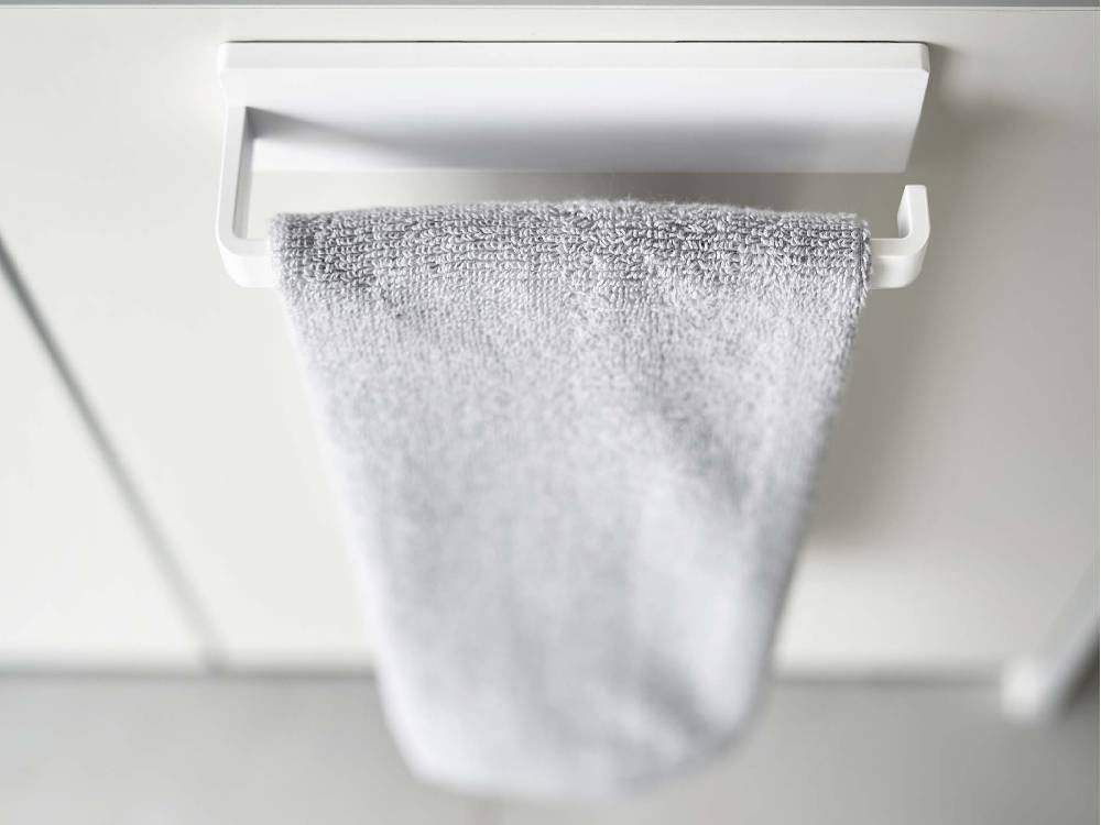 【MIST/ミスト】フィルムフック タオルハンガー W18が光沢のある壁面に取り付けられ、タオルを掛けている様子