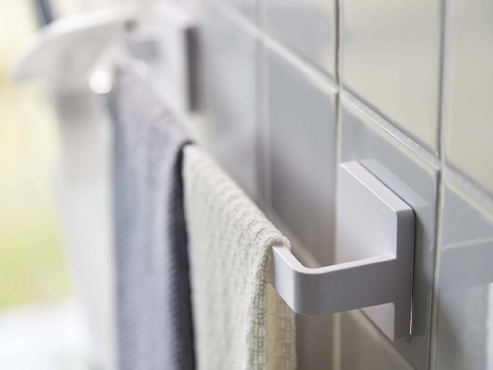 バスルームのタイル壁に取り付けられた銀色のタオルハンガーとトイレットロールホルダー