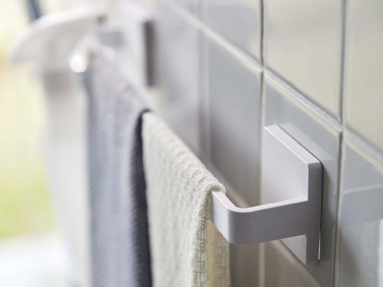 バスルームのタイル壁に取り付けられた銀色のタオルハンガーとトイレットロールホルダー