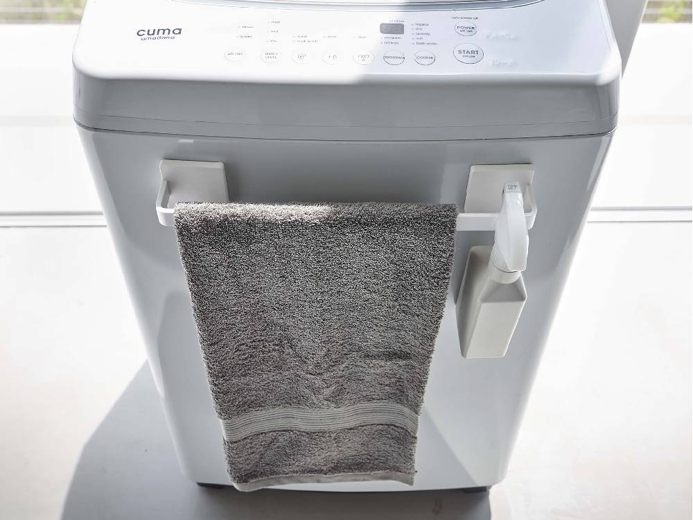 洗濯機や衣類乾燥機、シンクが配置された洗面所に、MISTフィルムフック タオルハンガーが設置されている様子