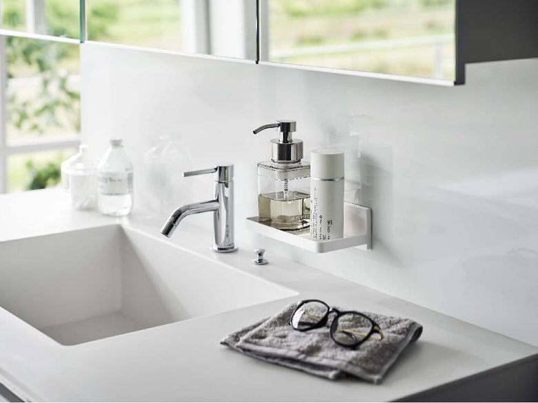 バスルームのシンクと蛇口が取り付けられたカウンタートップに、ソープディスペンサーやボトルが配置されている様子