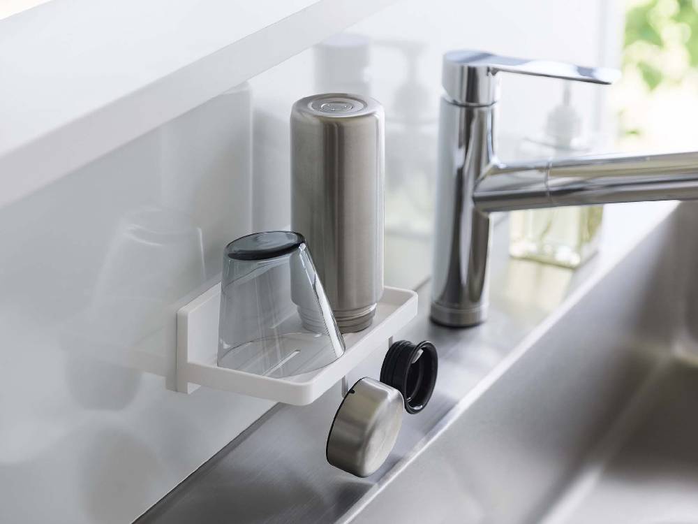 キッチンのシンクと蛇口、カウンタートップに置かれた家庭用ハードウェアと瓶