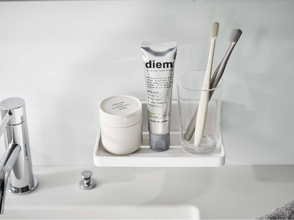 浴室用フィルムフックトレーに歯ブラシ、ソープディッシュ、ボトルなどの生活用品が整理整頓されて配置されている様子