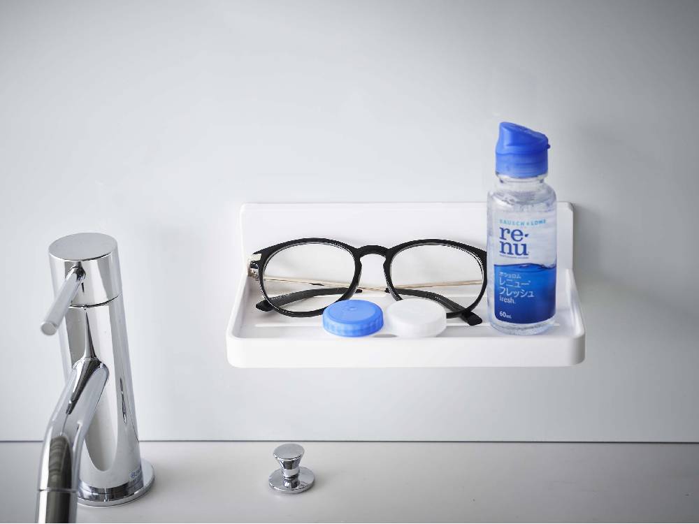 浴室の壁に設置されたMISTフィルムフックトレーW18に、ソープディスペンサーやプラスチックボトルが掛けられている様子