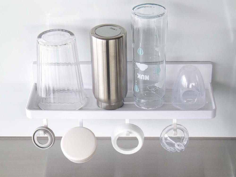 キッチンの棚に設置された【MIST/ミスト】フィルムフック トレー W30に、プラスチックや銀色の調理器具が整理されています