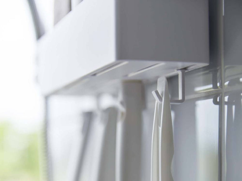 グレーとシルバーの【MIST/ミスト】フィルムフックラック W30がガラス窓に設置され、カーテンが美しく掛かっている様子