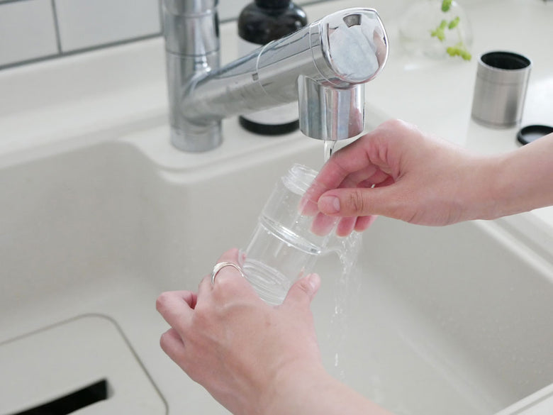 蛇口が取り付けられたキッチンシンクとボトルが配置された水回りの様子