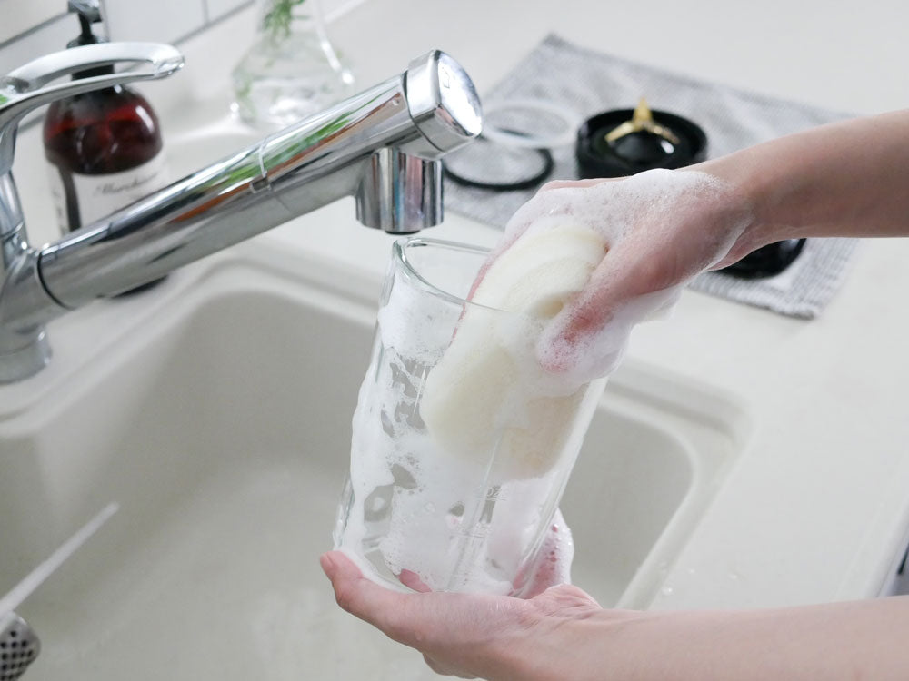 手で蛇口を操作して水を流すキッチンシンクの様子