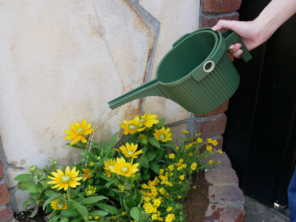 ひまわりやガーベニアとともに置かれた八幡化成のガーデンビートルフォンタナジョウロ