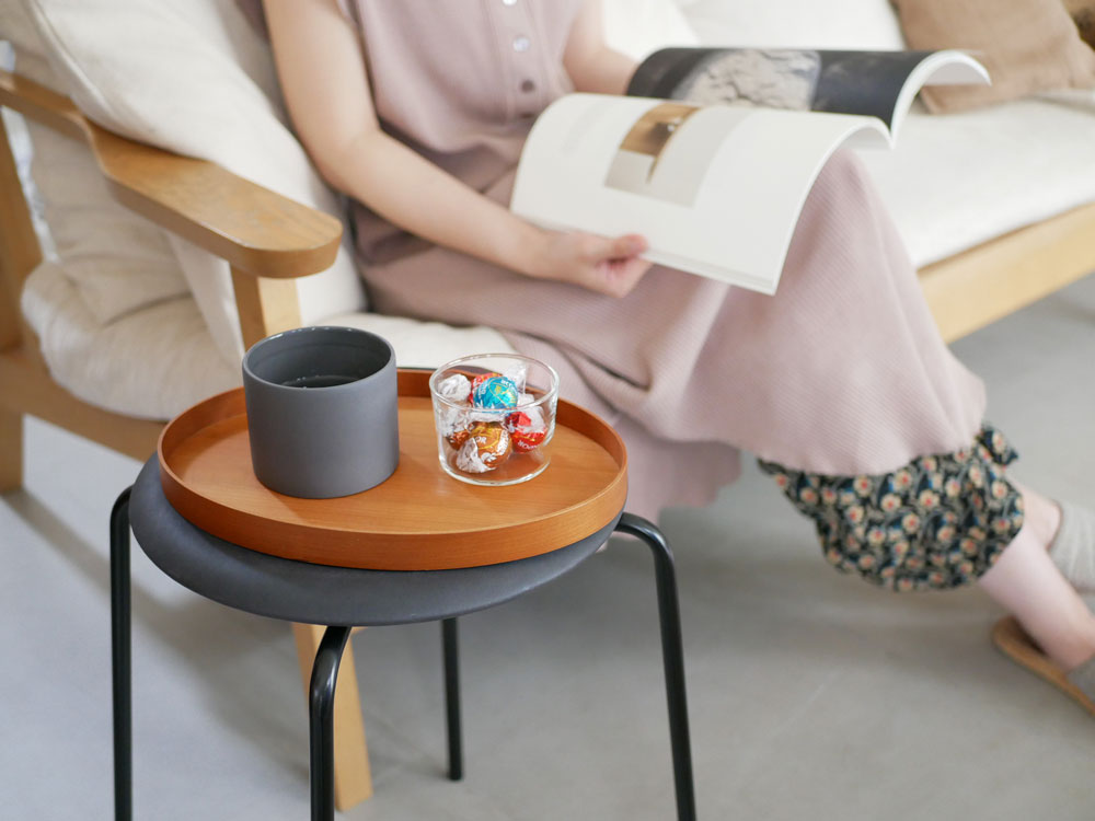 アルネ・ヤコブセンデザインのフリッツ・ハンセンDOTスツールがリビングルームに配置され、コーヒーテーブルやランプ、クッション、観葉植物とともに快適なインテリアを演出しています。