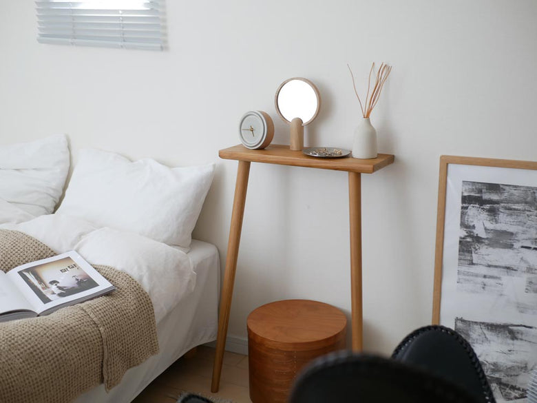 フリッツ・ハンセンのSkagerak Ainoミラーが木製のテーブルや観葉植物、ランプとともにスタイリッシュに配置された室内インテリア