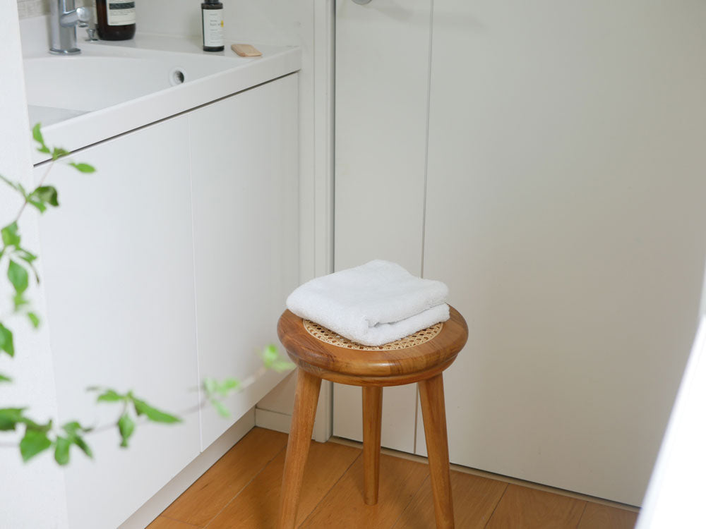 チーク材とラタンで作られた【サンフラワーラタン】ラタンスツールが木製フロアのある室内に配置された様子