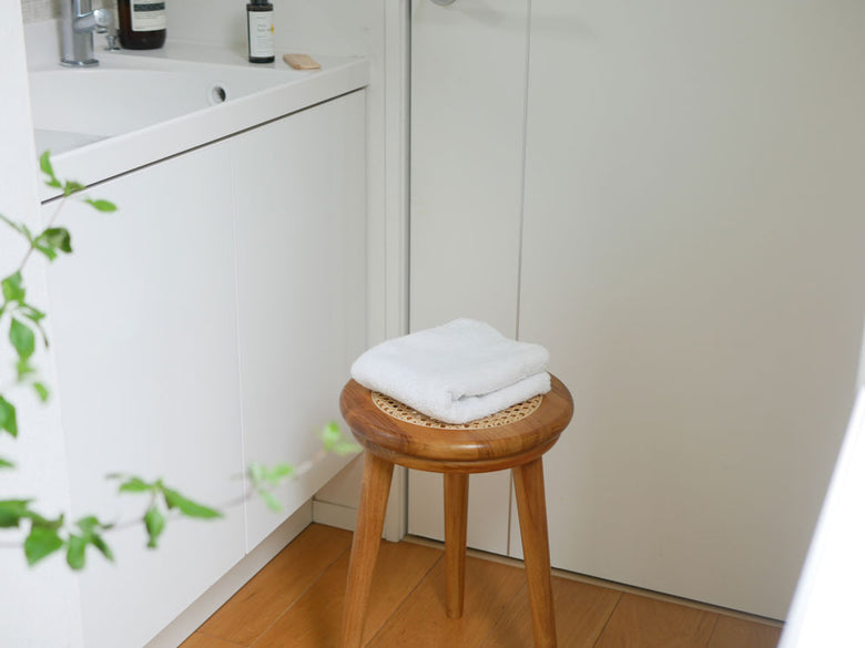 チーク材とラタンで作られた【サンフラワーラタン】ラタンスツールが木製フロアのある室内に配置された様子