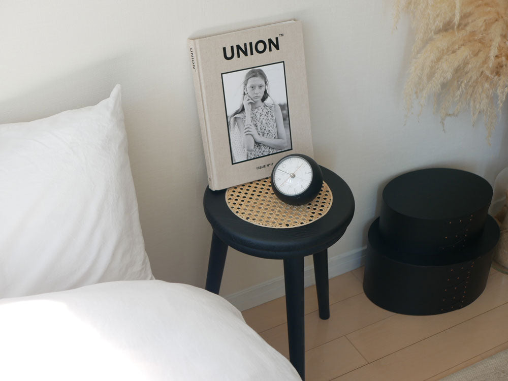 チーク材とラタンで作られたサンフラワーラタンのラタンスツールが木製コーヒーテーブルやランプ、クッションと共にリビングルームに配置されている様子