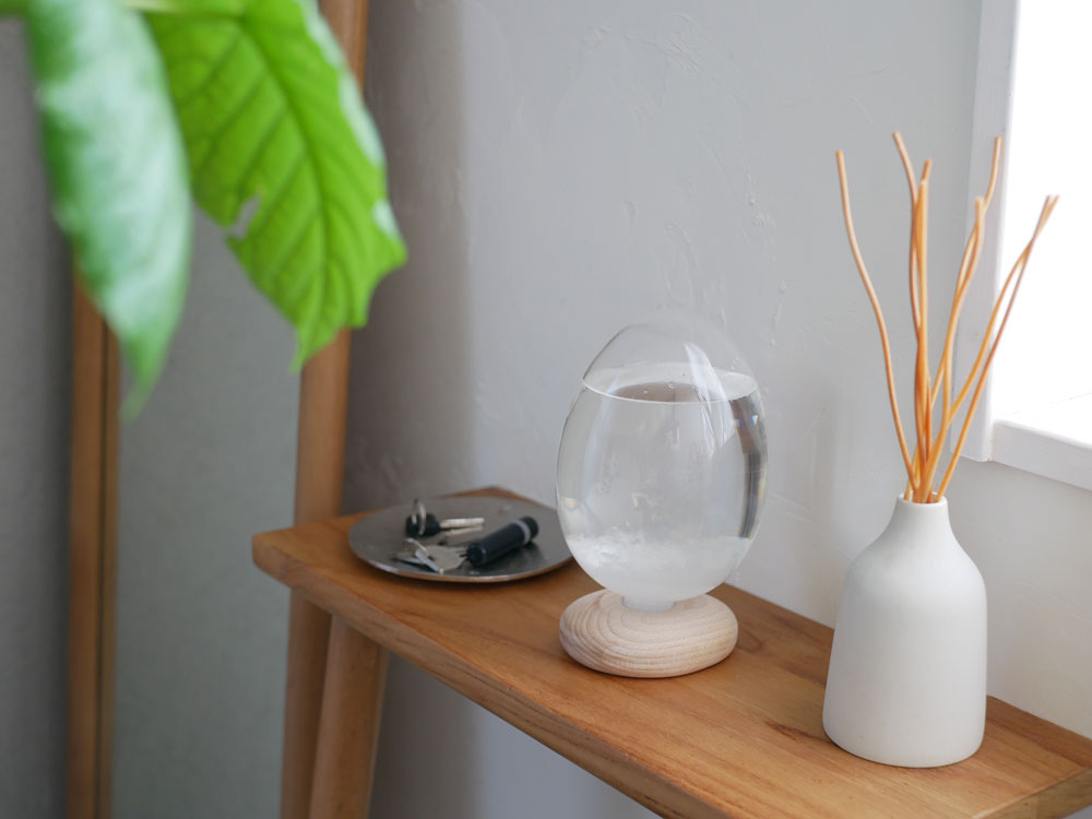 木製の基座に置かれたガラス製のTempo Dropミニで、内部の結晶が変化している様子