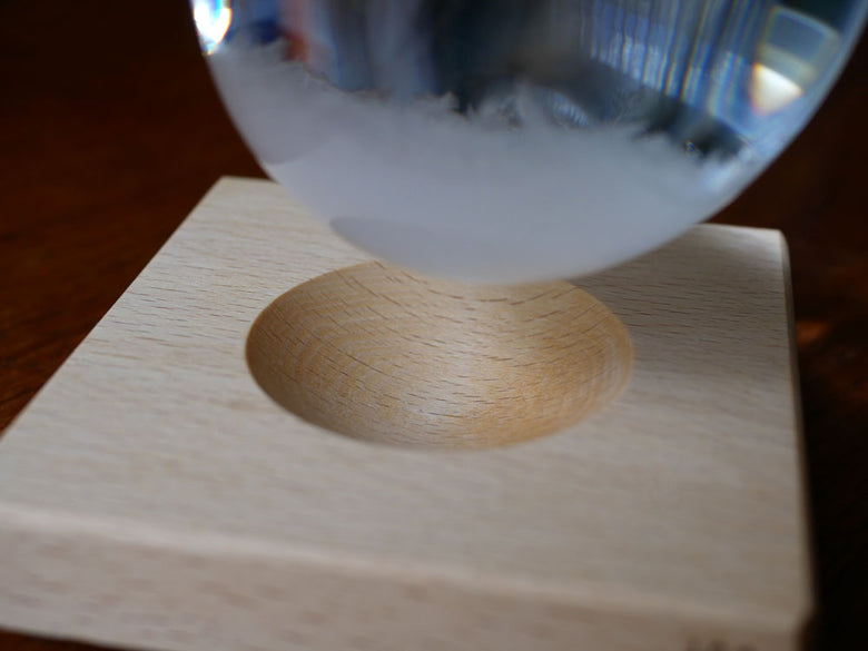 ヒャクパーセントのTempo Dropがビーチ材の木製台に置かれたガラス製の球体の静物写真