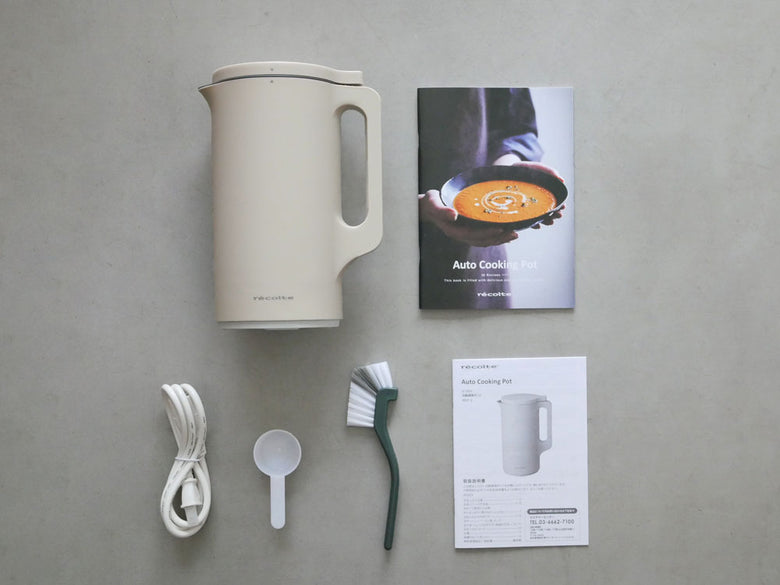 クリームホワイトの「recolte」自動調理ポットと計量スプーン、お手入れブラシがキッチンカウンターに並べられている様子