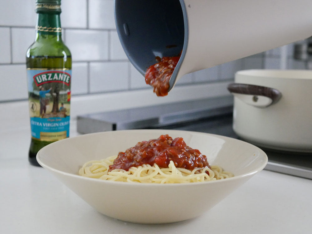 クリームホワイトの【recolte】自動調理ポットが食材や調理器具とともにキッチンテーブルに置かれている様子