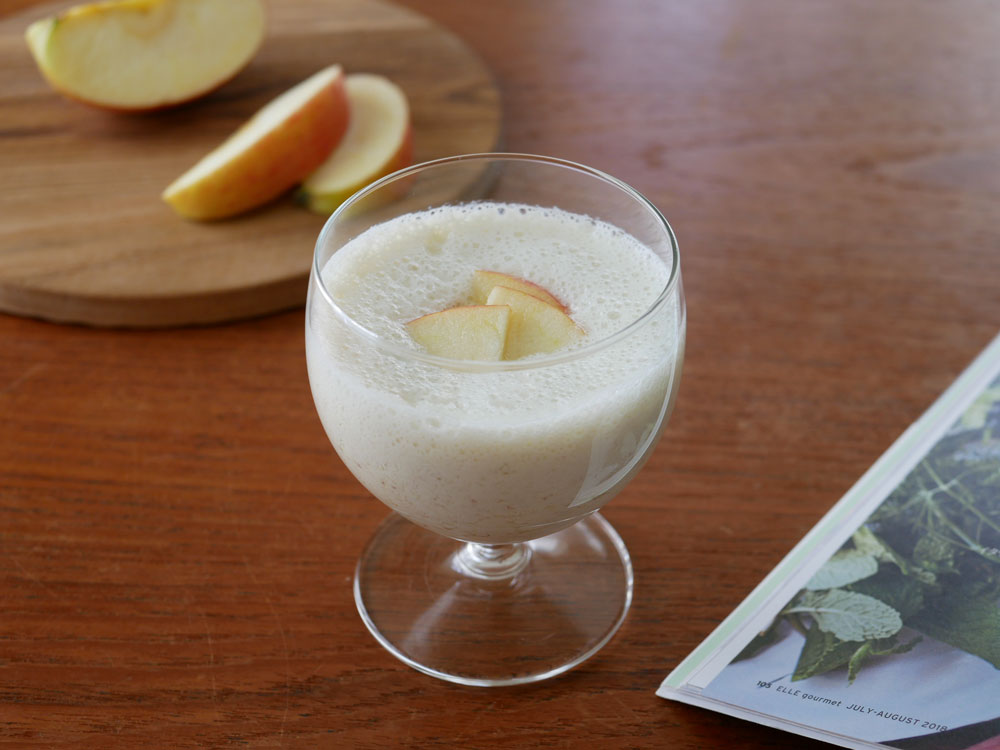 テーブルに【recolte】自動調理ポットが置かれ、フルーツや飲み物、食器などの食材が周囲に配置されている様子