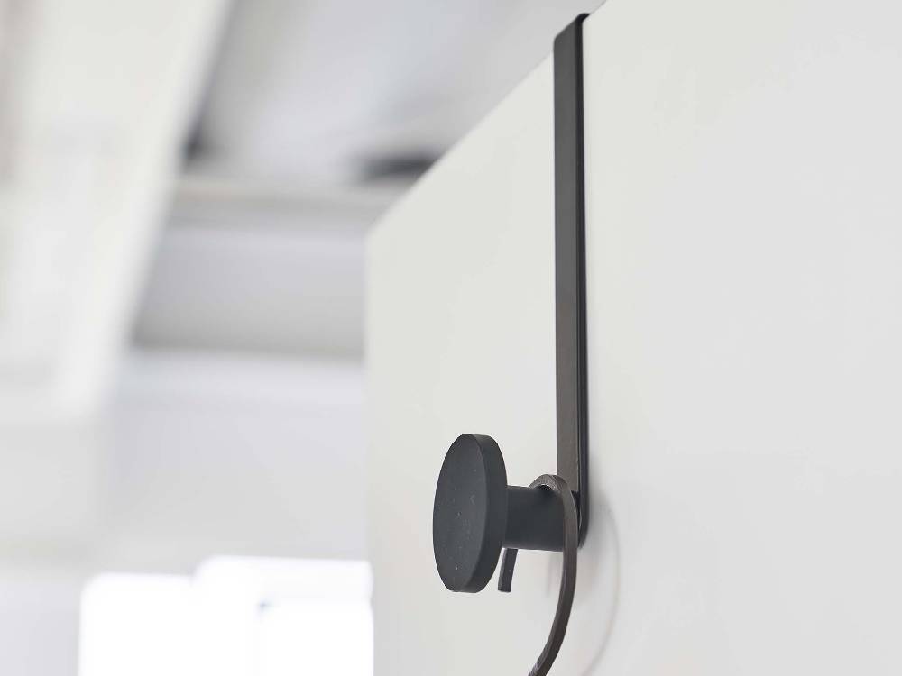 モダンなインテリア内にグレーの滑り止め付きスマートドアハンガーが取り付けられており、周囲には鏡や照明器具、棚などの家庭用ハードウェアが配置されています。