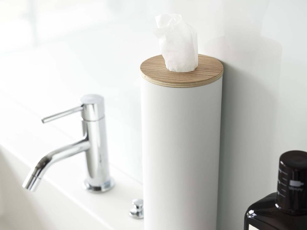 スチールと天然木で作られたボトル型ティッシュケース「RIN/リン」が洗面台に置かれ、周囲にタオルや観葉植物が配置されたバスルームの様子