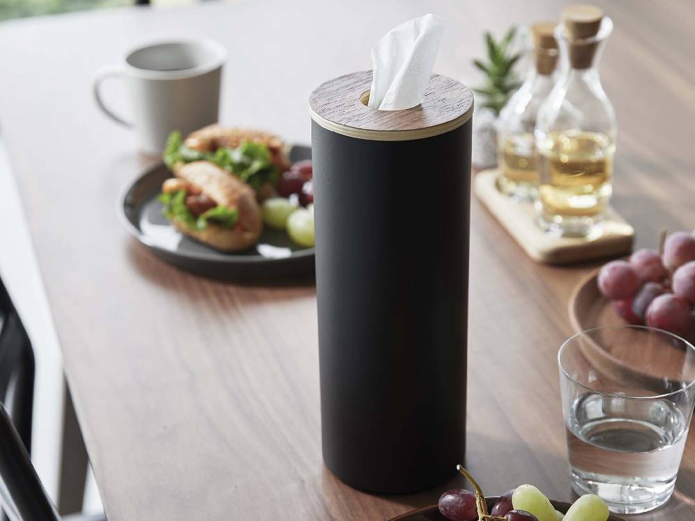 スチールと木材で作られたボトル型ティッシュケース Lが、カップやスプーン、ストローなどの食器と共にテーブルに配置されている