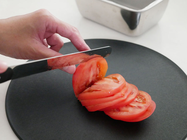 テーブルナイフを用いてまな板で野菜を切っている調理シーン