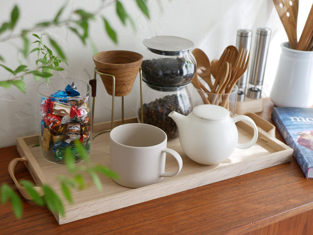 オークとレザー製のSkagerak Norr Trayに、陶器のカップやティーポット、バスケットが配置されたテーブルセット