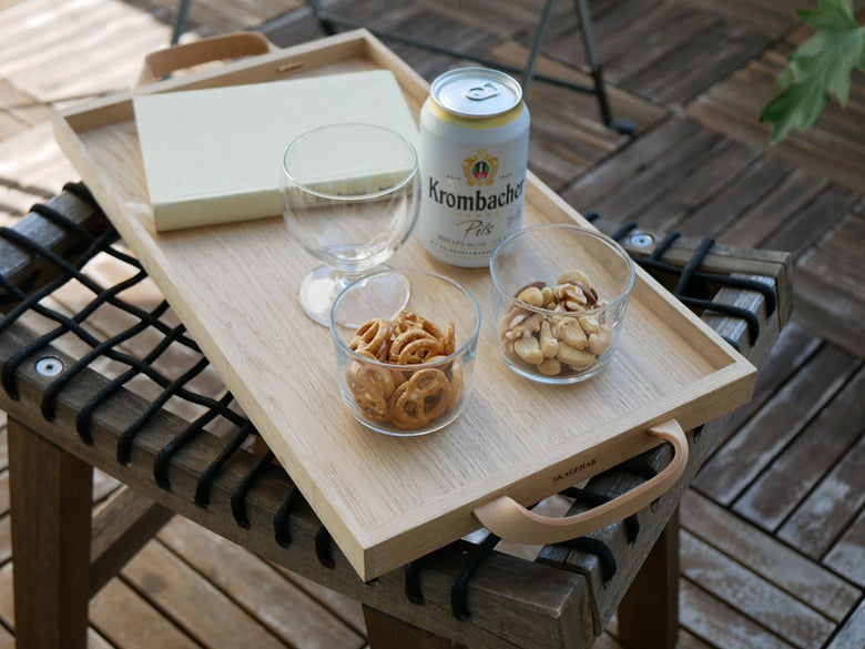 フリッツ・ハンセンのオークとレザー製Skagerak Norr Tray上にテーブルウェアや飲食物が配置されたテーブル