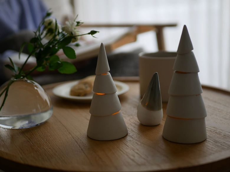 灯りが漏れる九谷焼のクリスマスツリー。緑豊かな松を模した三角形のデザインにLEDキャンドルが飾られています。