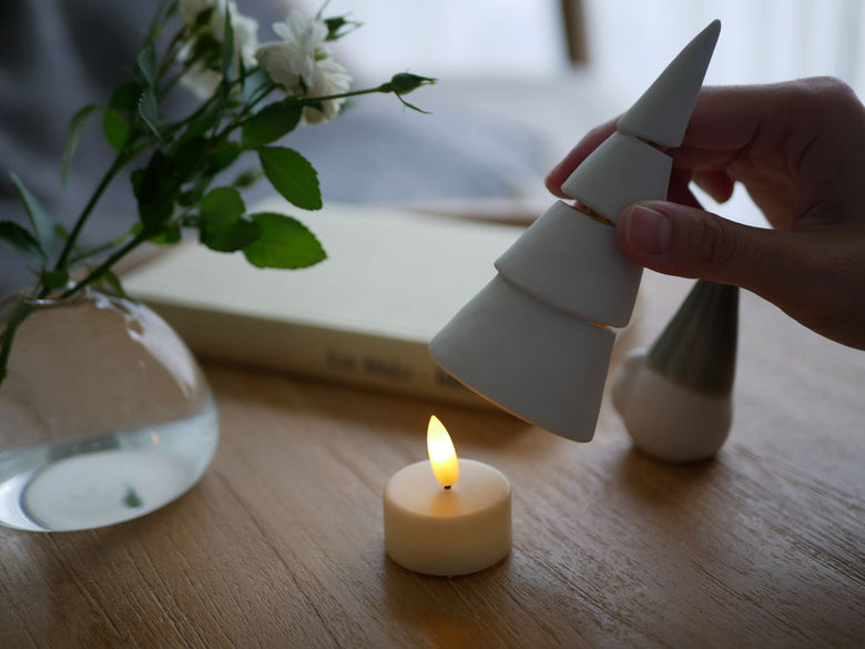 灯りが漏れる九谷焼のクリスマスツリーとLEDキャンドルの静物写真