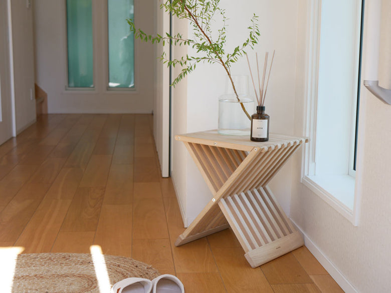 オーク材のFRITZ HANSENスカゲラック フィオニアスツールが木製フロアの上に配置され、観葉植物が添えられている様子