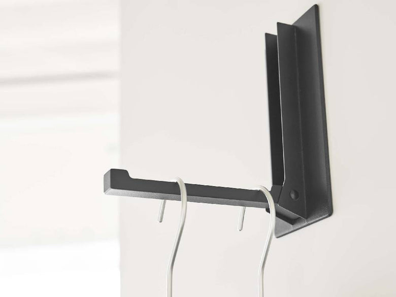 ホワイトのマグネット折り畳みハンガーがスチール製の棚に取り付けられている様子