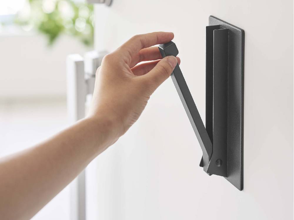 ホワイトのマグネット折り畳みハンガー『tower』がドアハンドルに取り付けられている様子