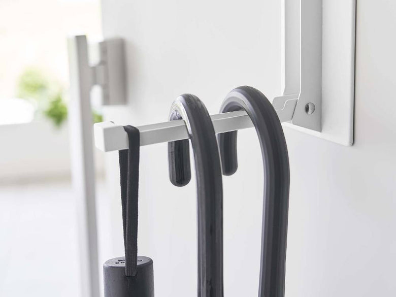 ホワイトのスチール製マグネット折り畳みハンガーが壁に取り付けられており、滑り止めシリコーンとマグネットが特徴的なデザイン