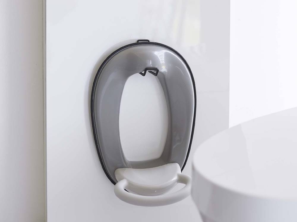 白色の陶器トイレに取り付けられたタワー製銀色フィルムフックトイレ用品収納フック。オーバル形状でバスルームのプラミング設備に調和。