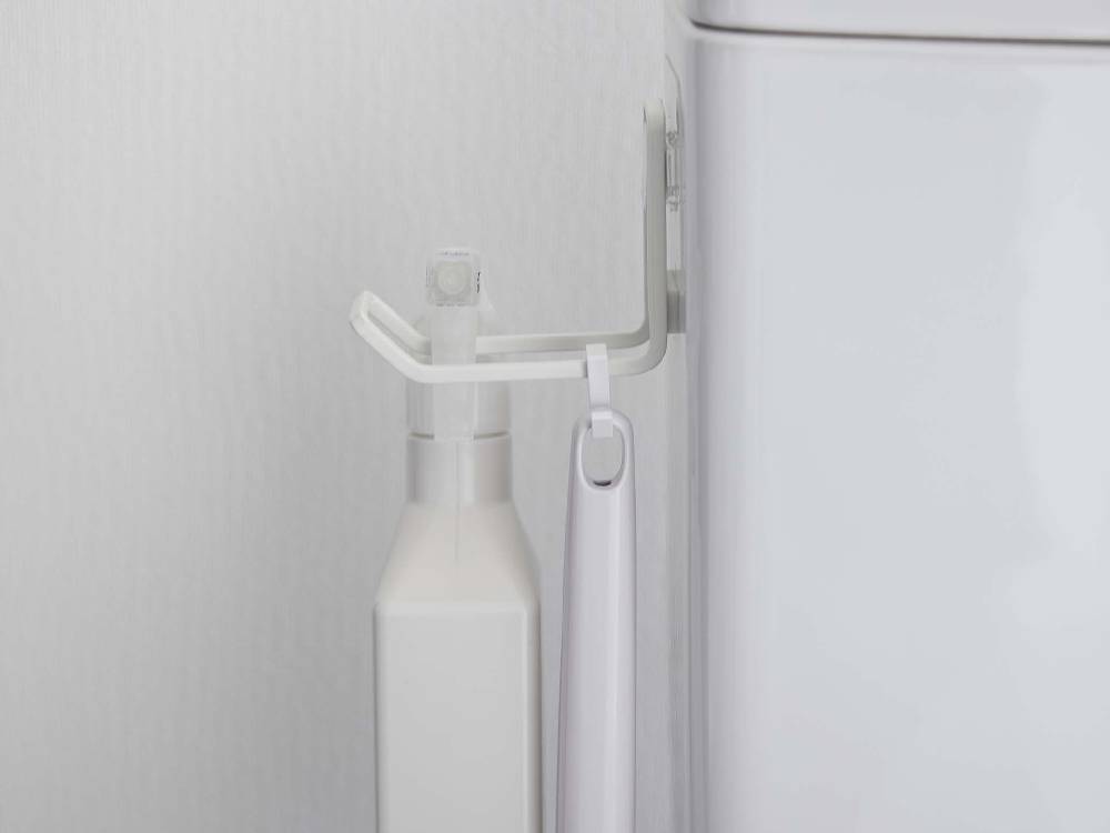 タワーのフィルムフックトイレ用品収納フックが浴室の洗面台近くの壁に取り付けられ、洗面用具やタオルが掛けられている様子