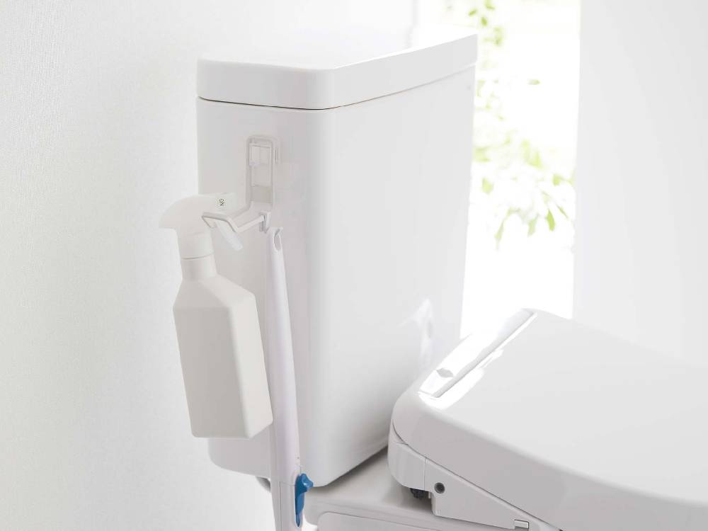 浴室の壁に設置されたタワー型フィルムフックトイレ用品収納フックに、トイレや洗面台の備品が掛けられている様子