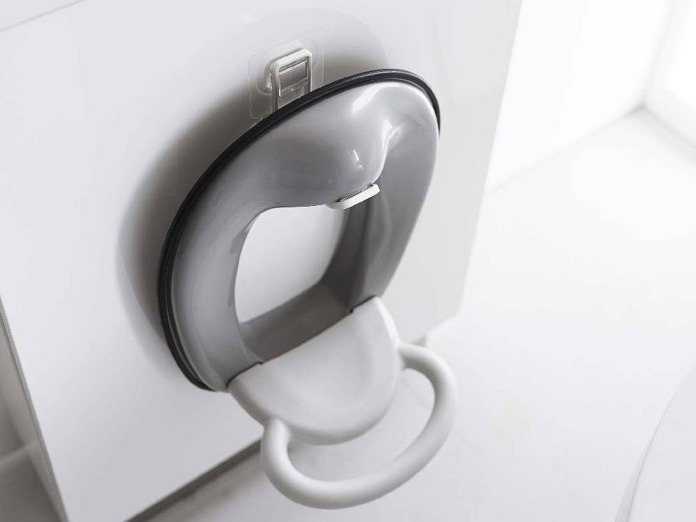 白色のタワーシリーズフィルムフックトイレ用品収納フックが銀色のトイレ便座に取り付けられている様子