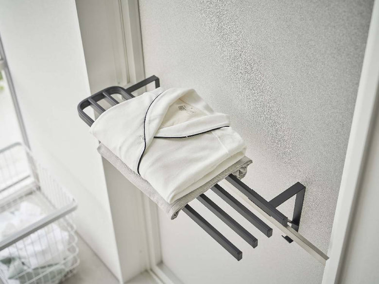 グレーの金属製タオルハンガーが浴室の扉に取り付けられ、バスタオルが掛けられている様子