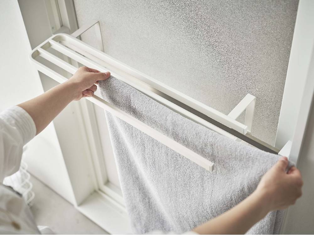 銀色のスチール製パイプバスタオルハンガーが浴室扉に掛けられている