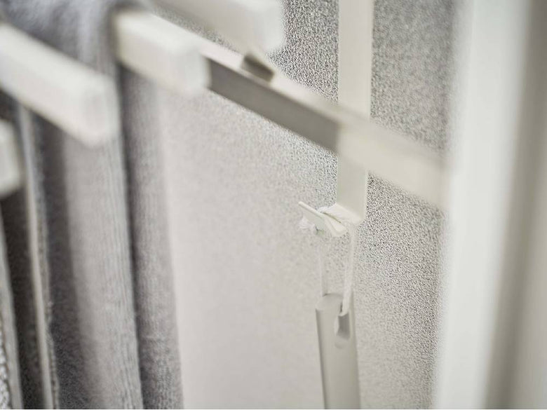 銀色の浴室扉に取り付けられたタワー型バスタオルハンガーの静物写真