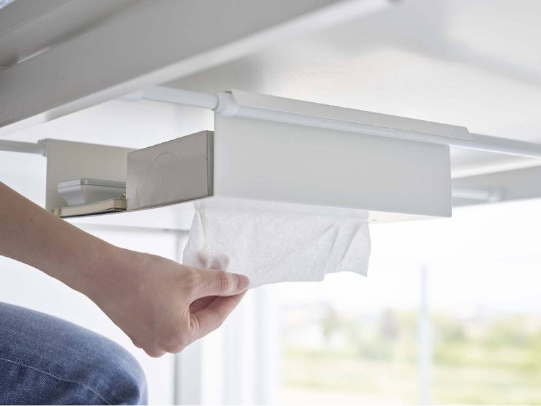 テーブル下に取り付けられたスチール製タワー型収納ラックに、紙タオルやティッシュペーパー、オフィス用品が整然と並べられている