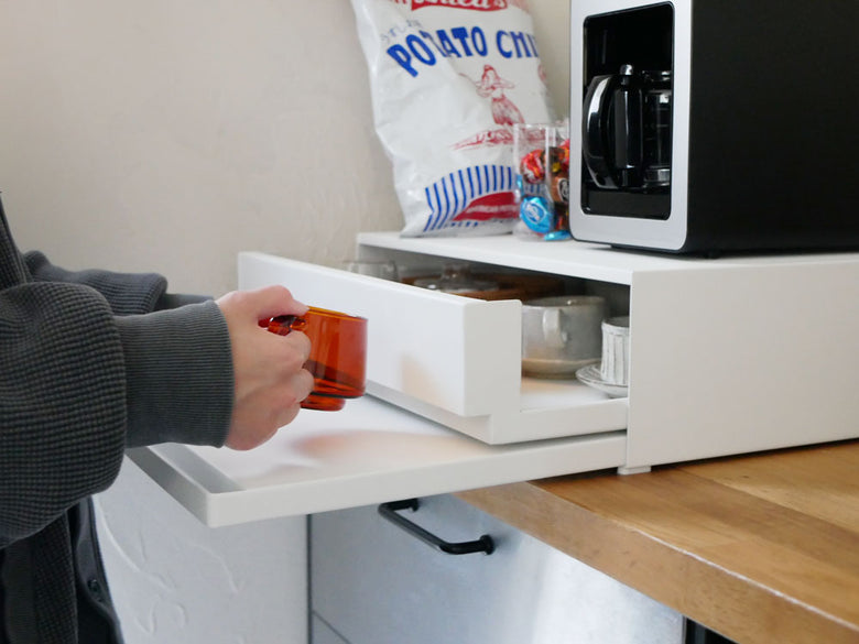 ツーウェイキッチン家電用スチールキャビネット。下部には引き出しとスライドテーブルが装備されており、ホワイトとブラックのカラー展開。