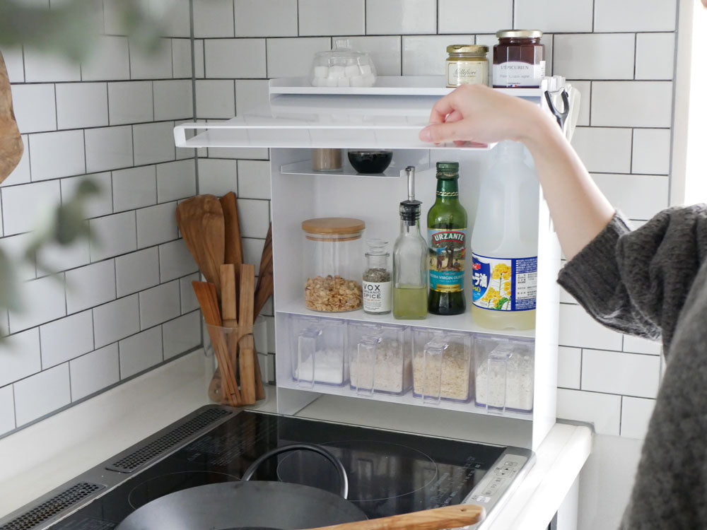 スチール製の前開き調味料ラックがキッチンのカウンタートップに設置され、複数の棚と調味料ボトルが整然と収納されている様子